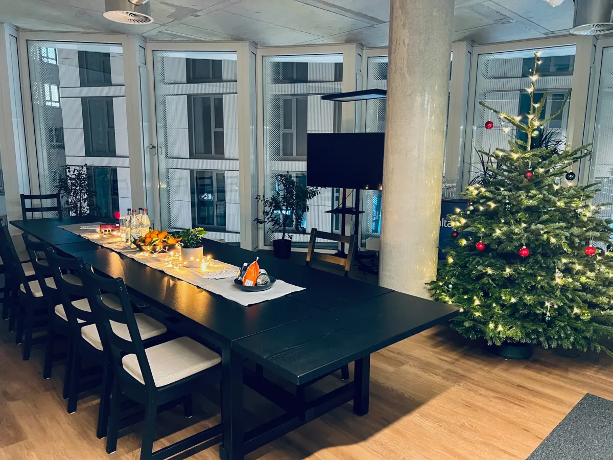 Gemeinschaftsbereich im AltaSigma-Büro mit langer Tafel und weihnachtlich geschmücktem Baum