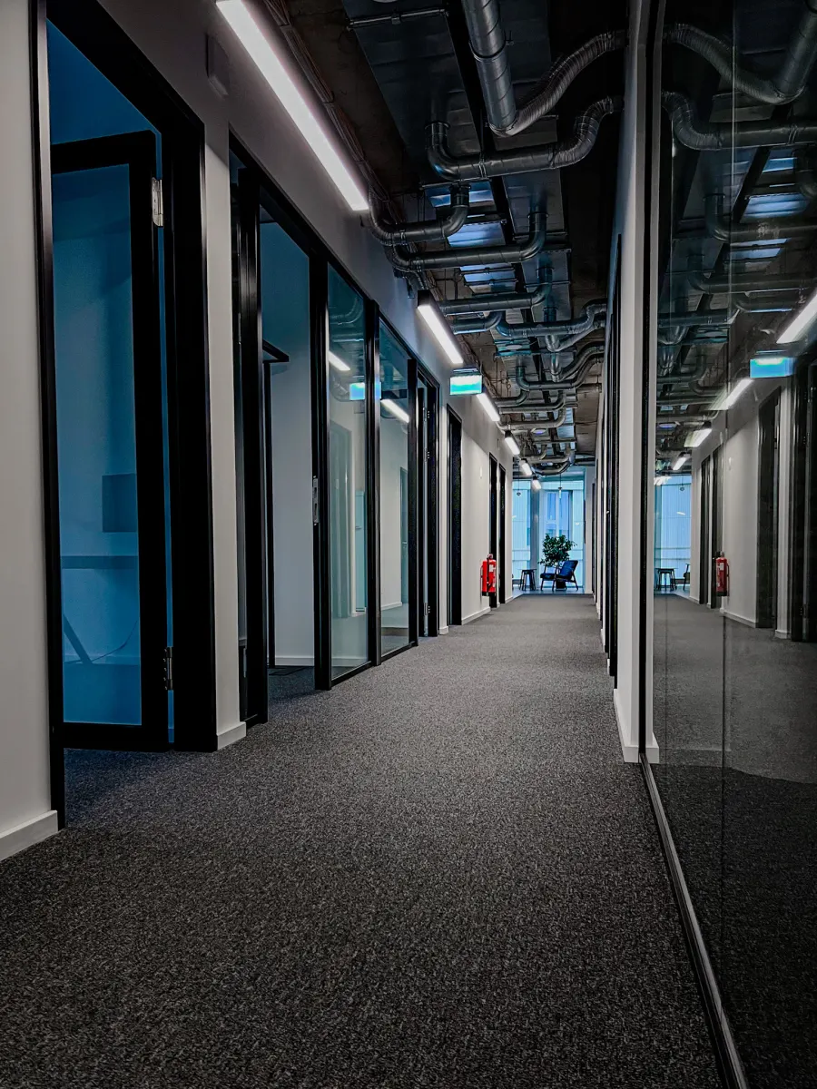 Moderner Büroflur mit verglasten Büros und offener Decke
